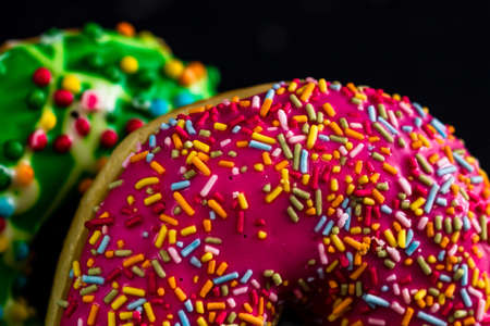 Fresh tasty colored donuts with sprinkles on black backgroundの写真素材