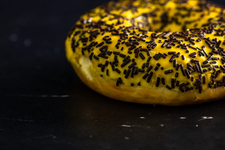 Fresh tasty colored donuts with sprinkles on black background