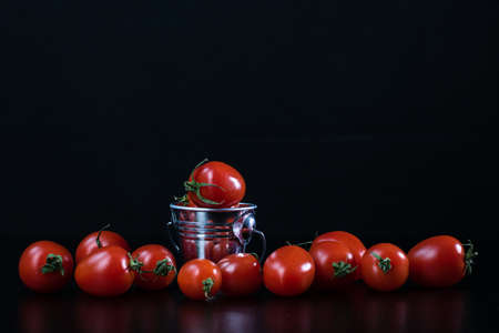 Selective focus on composition with mini decorative bucket and tomatoes. Small metal bucket with cherry tomatoesの写真素材