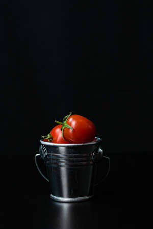 Selective focus on composition with mini decorative bucket and tomatoes. Small metal bucket with cherry tomatoesの写真素材