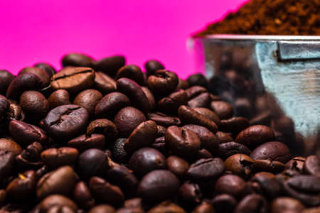 Coffee beans and portafilter with ground coffee in a composition on a pink background.の写真素材