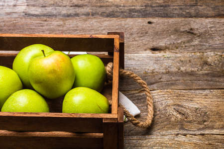 Wooden crate with ripe green apples on wooden table.の写真素材