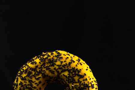 Fresh tasty colored donuts with sprinkles on black background