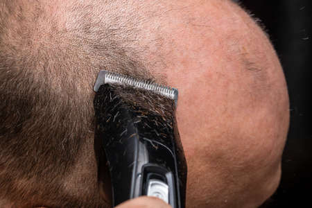 Man shaving or trimming his hair using a hair clipperの写真素材