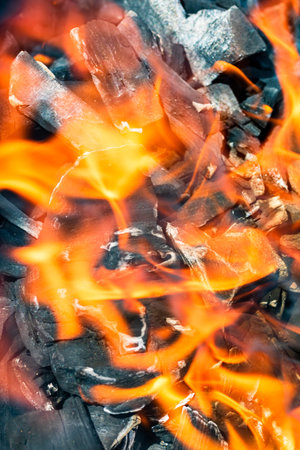 Barbecue grill pit with glowing and flaming hot open fire with red flame, hot charcoal briquettes...