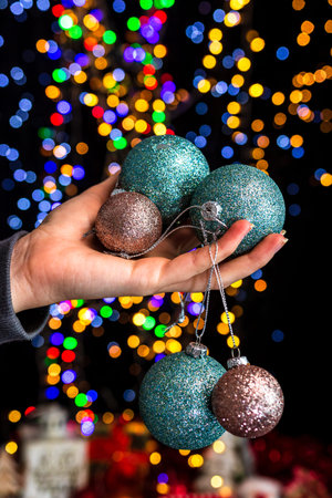 Holding Christmas decoration against bokeh lights background