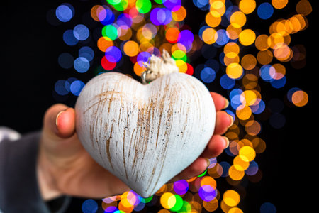 Holding Christmas decoration against bokeh lights backgroundの写真素材