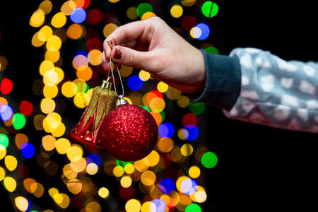 Woman's hands hold christmas decoration. Christmas and New Year holidays background, winter season with Christmas ornaments and blurred lightsの写真素材