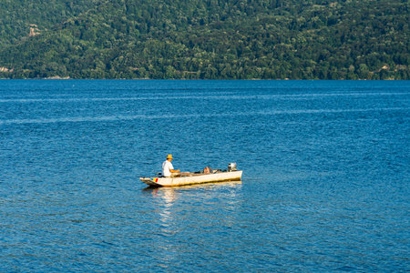 Man in boat relaxing and fishing on Danube river on a sunny day in Orsova, Romania, 2020.