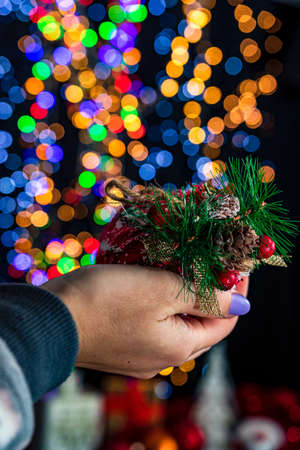 Holding Christmas bauble decoration isolated on background with blurred lights. December season, Christmas composition.の写真素材