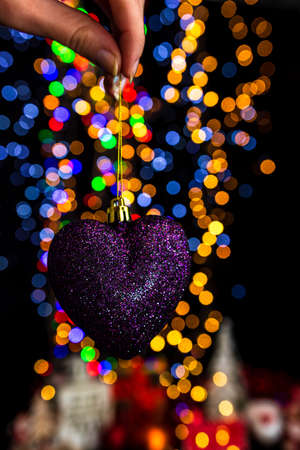 Holding Christmas decoration against bokeh lights backgroundの写真素材