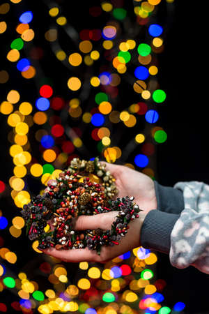 Woman's hands hold christmas decoration. Christmas and New Year holidays background, winter season with Christmas ornaments and blurred lightsの写真素材
