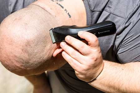 Male shaving or trimming his hair using a hair clipper or electric razor