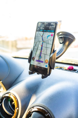 Using waze maps application on smartphone in car dashboard. Driver using maps app for showing the...