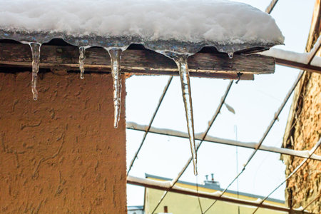 Roof covered with snow, icicles on roof isolated close up.