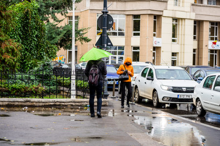 People with umbrella on the street on a rainy day in Bucharest, Romania, 2021