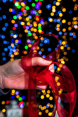 Holding Christmas decoration against bokeh lights backgroundの写真素材