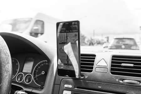 Using waze maps application on smartphone on car dashboard, Driver using maps app for showing the right route through the traffic of city on a rainy evening. Bucharest, Romania, 2020.のeditorial素材