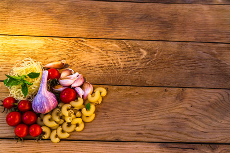 Pasta ingredients on wooden table. Cherry tomato, onion, garlic