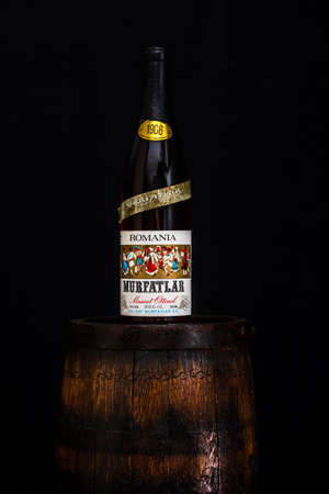 Vintage Murfatlar wine bottle on wooden barrel with dark background. Illustrative editorial photo Bucharest, Romania, 2021のeditorial素材