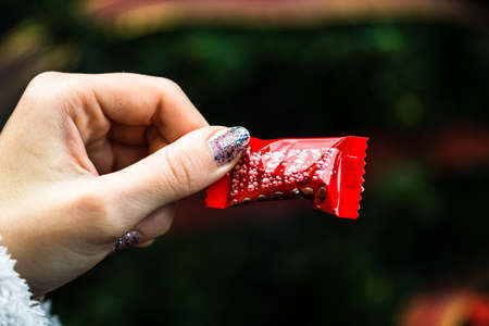 Hand holding chocolate candies in front of the Christmas tree. Candies for Chritmas in Bucharest, Romania, 2021のeditorial素材