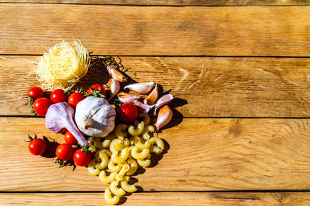 Pasta ingredients on wooden table. Cherry tomato, onion, garlicの写真素材