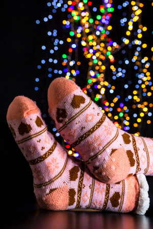 Legs in winter Christmas socks on blurred lights
