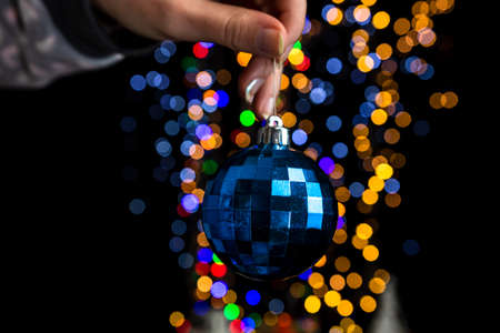 Holding Christmas decoration against bokeh lights backgroundの写真素材