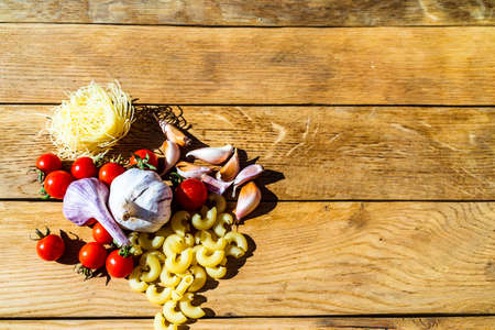 Pasta ingredients on wooden table. Cherry tomato, onion, garlicの写真素材