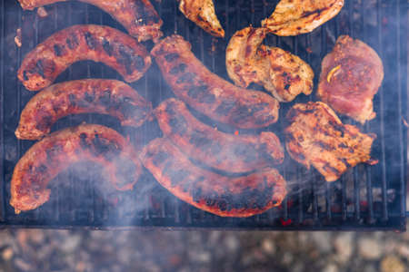 Grilling sausages and pork chops on barbecue grill. BBQ in the gardenの写真素材