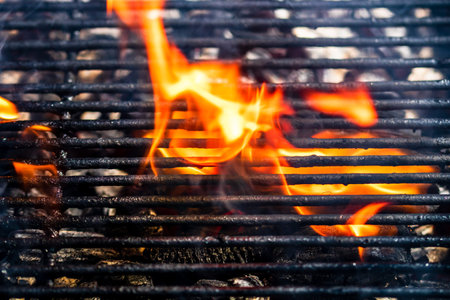 Empty hot charcoal barbecue grill with bright flame. Hot burning grill, outdoors cooking food