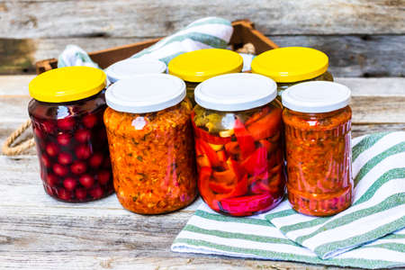 Jars with variety of canned vegetables and fruits, jars with zacusca. Preserved food concept in a rustic composition.の写真素材