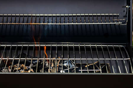 Barbecue grill pit with glowing and flaming hot open fire with red flame, hot charcoal briquettes and embersの写真素材