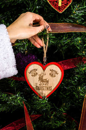 Decorating Christmas tree, hand putting Christmas decorations on fir branches. Christmas hanging decorations.の写真素材