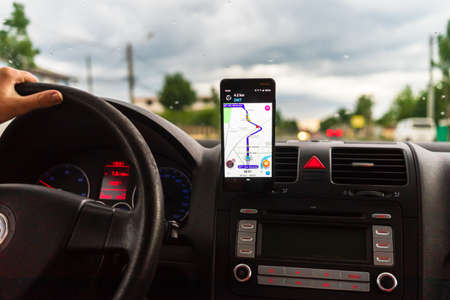 In car dashboard view with smartphone on Waze maps. Driver using Waze maps in Bucharest, Romania, 2022のeditorial素材