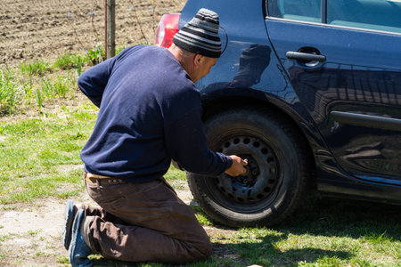 Mechanic changing wheel on car with manual wrench. Mechanic replacing tires in Bucharest, Romania, 2021のeditorial素材
