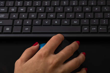 Hand using pc mouse. Close up hand on computer mouse on black wooden backgroundのeditorial素材