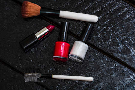 Cosmetics on a black, nail polish, eye shadow palette, lipstick, brush, parfumeの写真素材