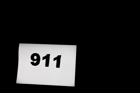 Call 911 and emergency call concept, text 911 on paper isolated on black.