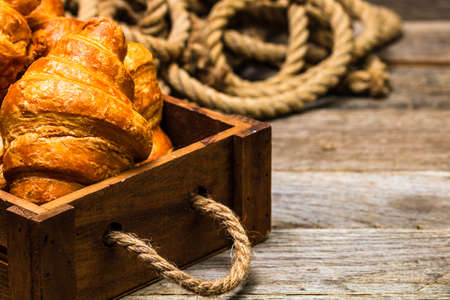 Wooden crate with delicious, fresh croissants isolated. French breakfast concept.の写真素材