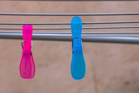 Colorful plastic clothes pegs on empty metal clothes dryer.