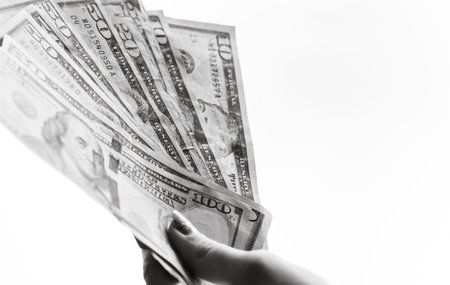 Woman hand giving money like bribe or tips isolated on white background. USD currency banknotes close up. Reward for hard work, finance and business conceptの写真素材