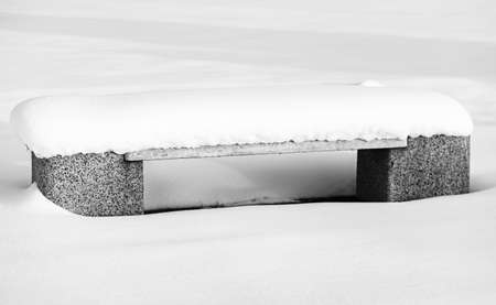 Snow-covered bench in the park. Park bench covered with snow from the first snow fall of the yearの写真素材