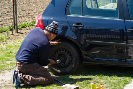 Mechanic changing wheel on car with manual wrench. Mechanic replacing tires in Bucharest, Romania, 2021のeditorial素材
