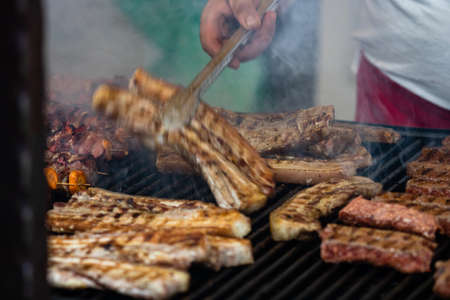 Grilling tasty food on barbecue. Steak, sausages on grill at food festivalの写真素材