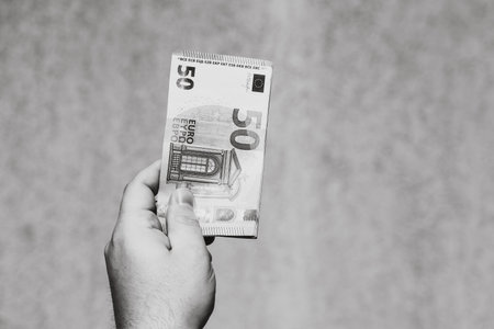 Hand holding showing euro money and giving or receiving money like tips, salary. 50 EURO banknotes EUR currency isolated. Concept of rich business people, saving or spending money.の写真素材