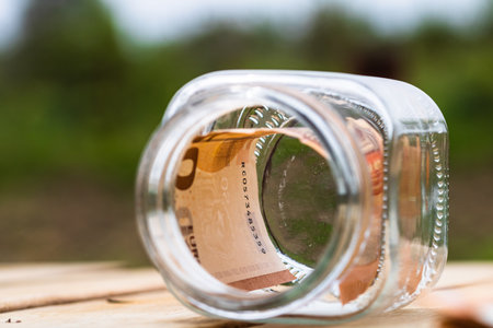 Composition with saving money banknotes in a glass jar. Concept of investing and keeping money, close up isolated.の写真素材