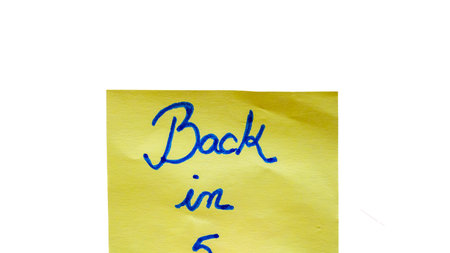 Back in five handwriting text close up isolated on yellow paper with copy space.