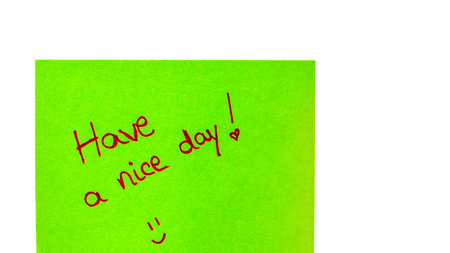 Havce a nice day handwriting text close up isolated on green paper with copy space. Writing text on memo post reminderの写真素材