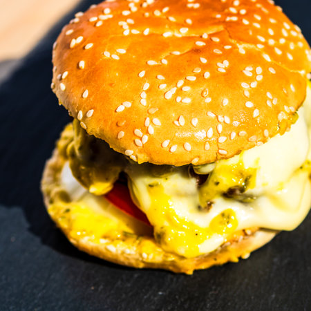 Tasty home made cheeseburger. Cheese burger with pickles, tomatoes, onion, melting cheeseの写真素材
